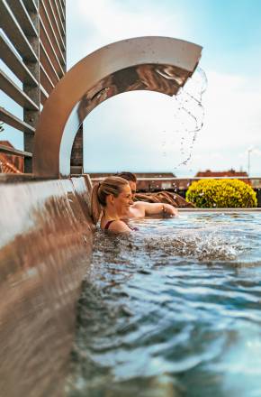 Personen sitzen im Außenpool vom Hotel Helvetia