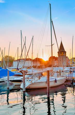 Verschiedene Boote liegen im Hafen von Lindau bei der Abendsonne